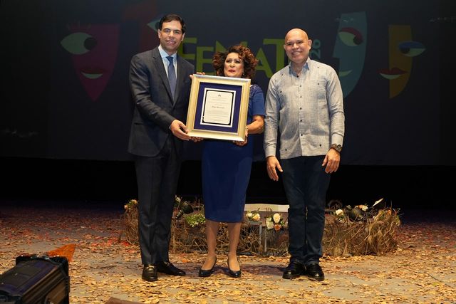 Olga Bucarelli sostiene la placa de reconocimiento del Fenate 2026 junto al ministro de Cultura, Roberto Ángel Salcedo, y el viceministro Amaury Sánchez