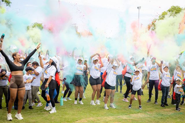 Participantes lanzan polvos de colores al aire