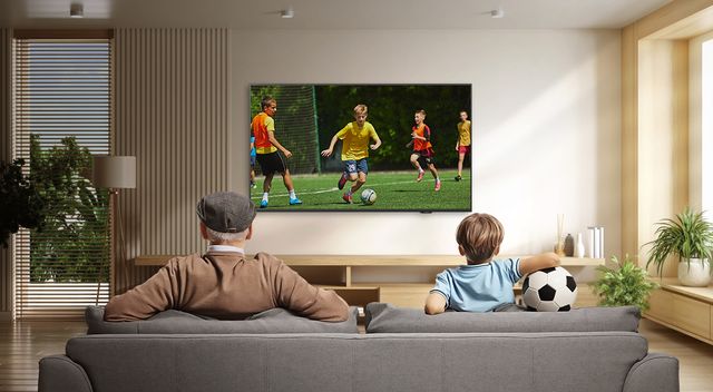Familia ve un partido de fútbol en un televisor Samsung en la sala