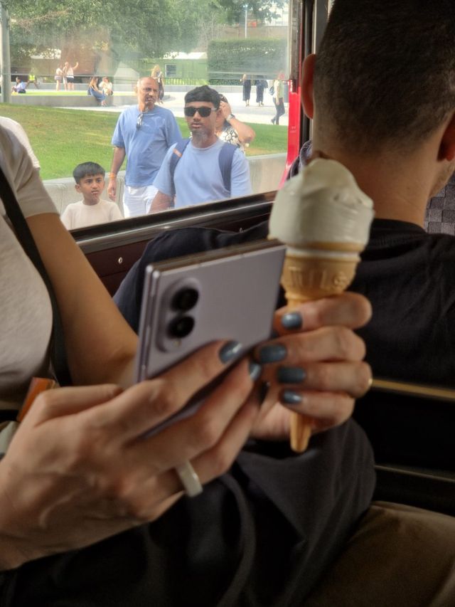 Una pasajera de autobús sostiene un Galaxy Z Fold8 color lila y un helado de barquilla
