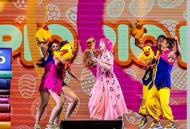 Luli Pampín y bailarines disfrazados en un escenario colorido