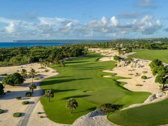 Calles y bunkers de Punta Espada Golf Club entre palmeras, con el mar al fondo