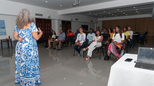 Una expositora se dirige a los asistentes en un salón