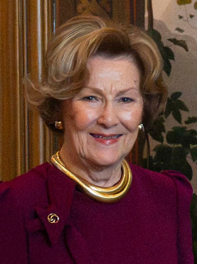 La reina Sonia de Noruega sonríe con un vestido burdeos y un collar dorado durante una audiencia en Oslo en 2025