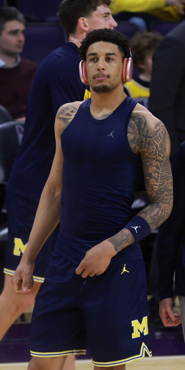 Yaxel Lendeborg, con uniforme de calentamiento de Michigan y audífonos rosados, en la cancha del Welsh–Ryan Arena