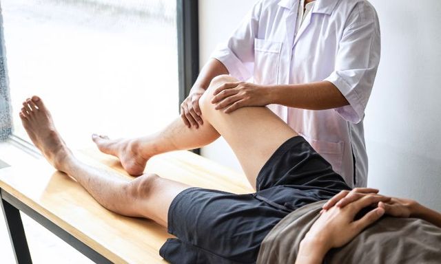 Un fisioterapeuta trabaja con la pierna de un paciente