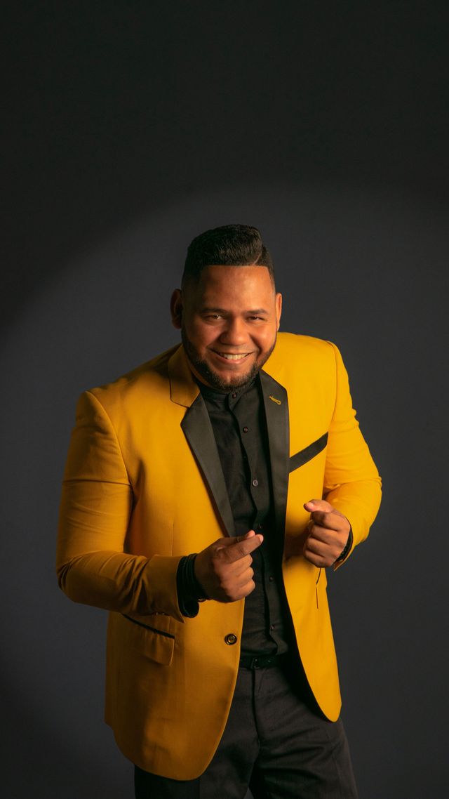 Wilbert Taveras sonríe con chaqueta amarilla y camisa negra