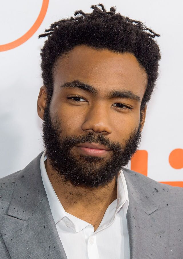 Donald Glover, con barba y saco gris, posa en una alfombra roja