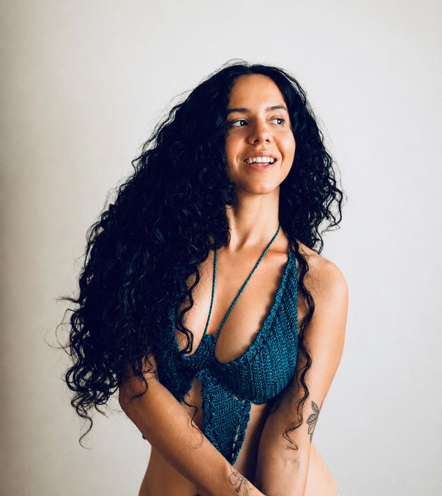 La Marimba sonríe con traje de baño tejido azul sobre fondo claro