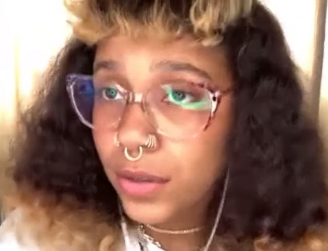 Tokischa, con lentes transparentes y el pelo rizado, durante una entrevista virtual en 2021