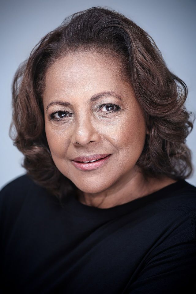 Retrato de la actriz Lidia Ariza, de cabello castaño ondulado y blusa negra, sobre fondo gris