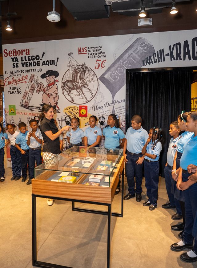 Una guía habla a un grupo de estudiantes frente a un mural histórico de Cortés