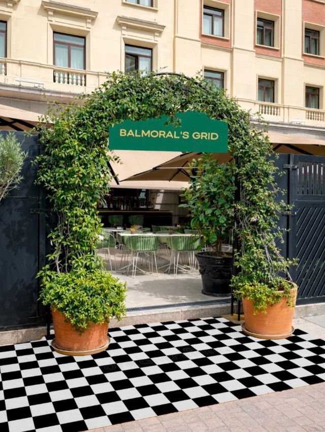 Arco de plantas con el letrero de Balmoral's Grid sobre un piso a cuadros