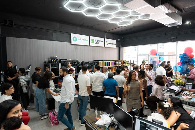 Invitados recorren la tienda de 3D Printers RD bajo las luces hexagonales del techo
