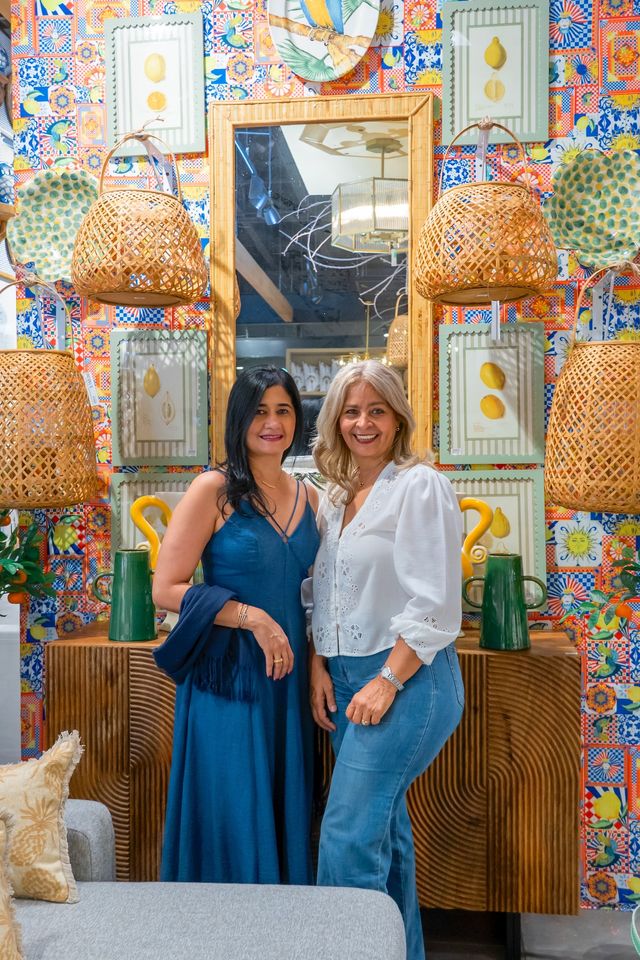 Mariel Paulino y Amalia De Los Santos frente a una pared decorada con cestas y azulejos