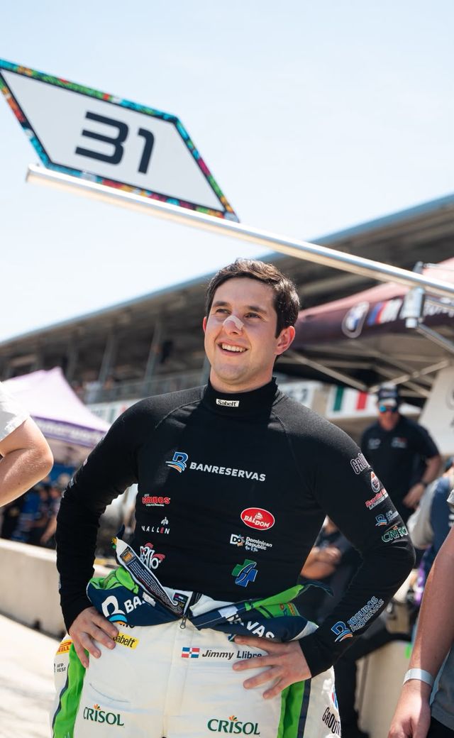 El piloto dominicano Jimmy Llibre sonríe en la recta de boxes con su traje de carreras