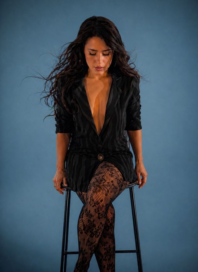 Celeste Sanazi sentada en un taburete sobre fondo azul