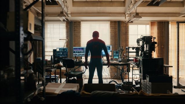 Spider-Man de pie en un taller lleno de pantallas y herramientas