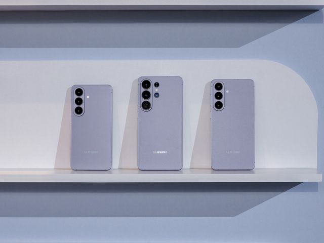 Tres teléfonos de la serie Galaxy S26 en color violeta sobre un estante blanco