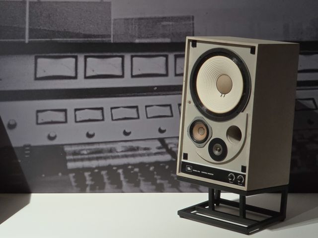 Monitor de estudio JBL 4310 frente a una foto en blanco y negro de una consola de grabación