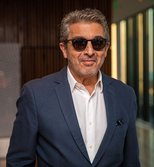 Ricardo Darín sonríe con gafas oscuras, saco azul marino y camisa blanca en Buenos Aires